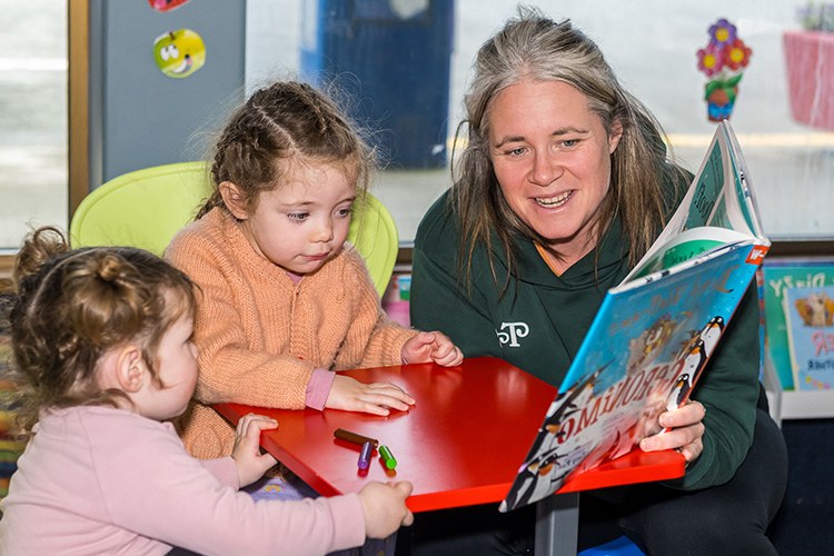 woman reads book to two small children