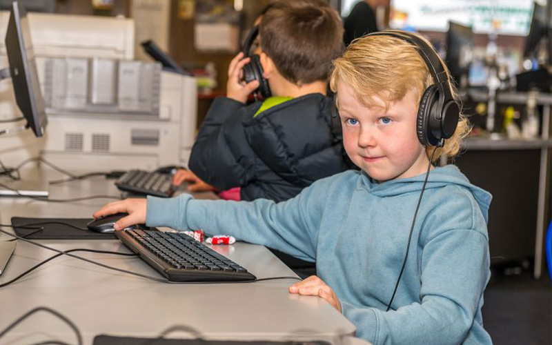 child wearing headphones on a computer